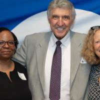 Dean Somill and Provost Drake pose for a photo with another guest in front of the GVSU backdrop